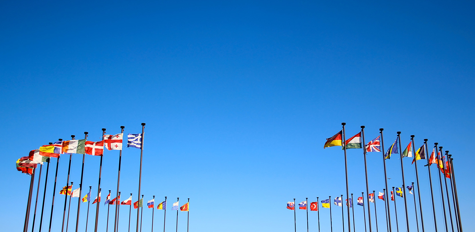 A ring of flags from different countries against a blue sky