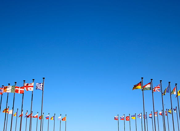 Ring of international flags against a blue sky