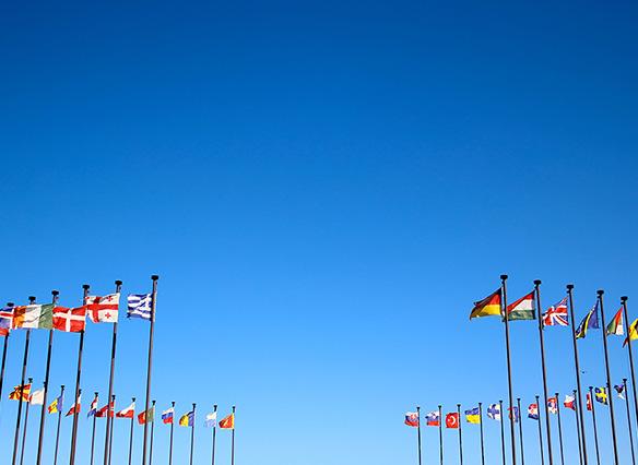 Ring of international flags against a blue sky